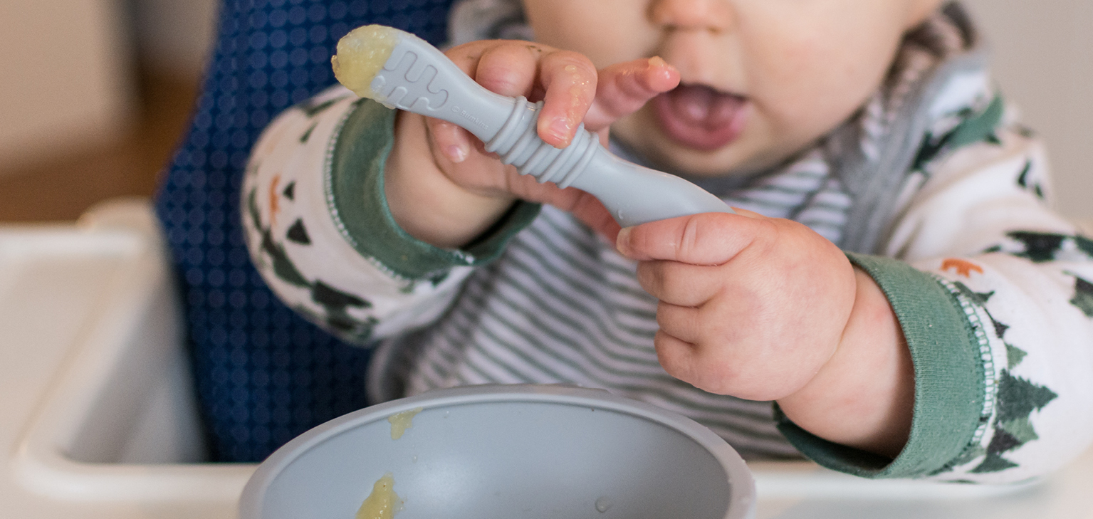 Bébé avec cuillière qui mange seul