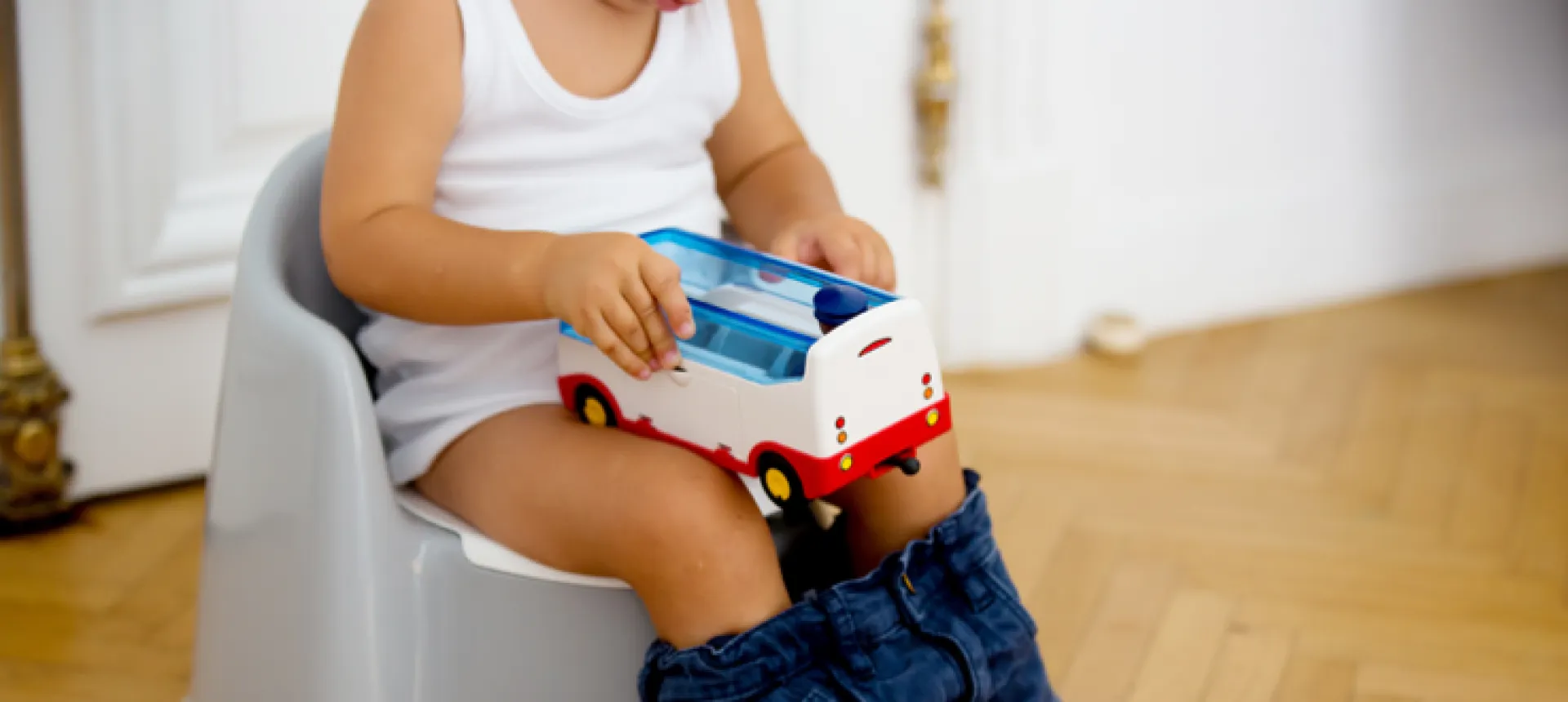 bebe-assis-sur-pot-tenant-jouet-camion