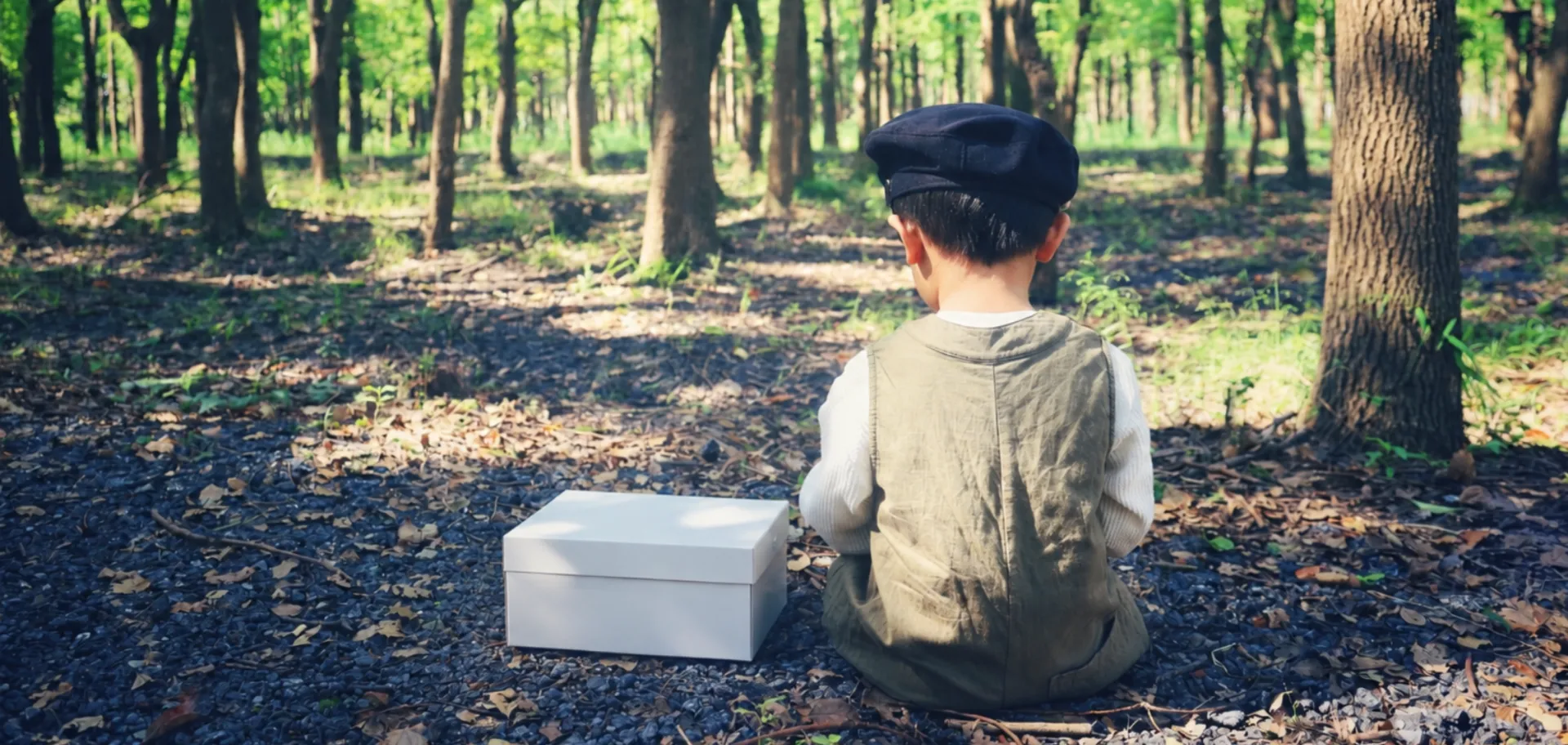 enfant-en-forêt-avec-sa-boite-en-carton