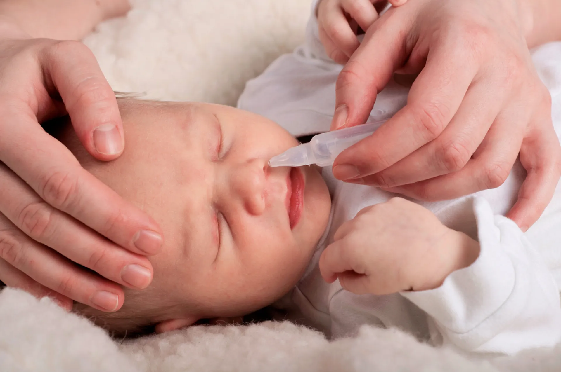 Adulte nettoyant le nez d'un bébé avec sérum physiologique 