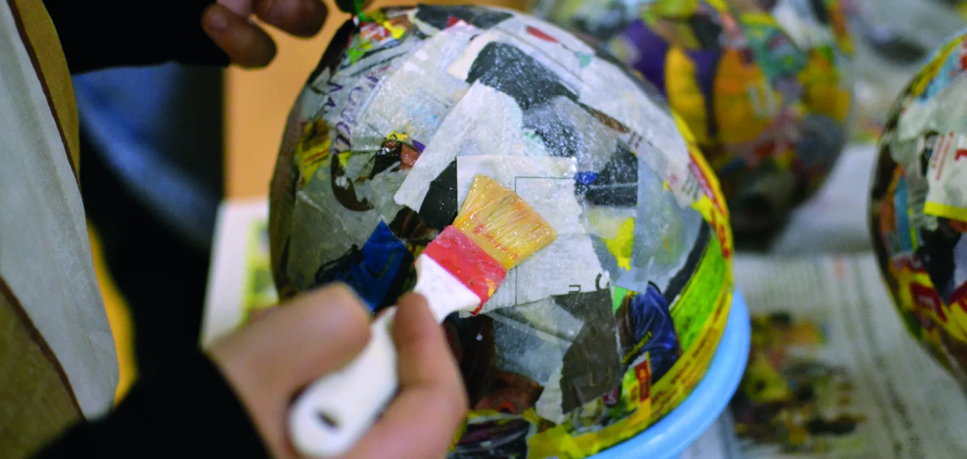 enfant qui fabrique un œuf en papier maché