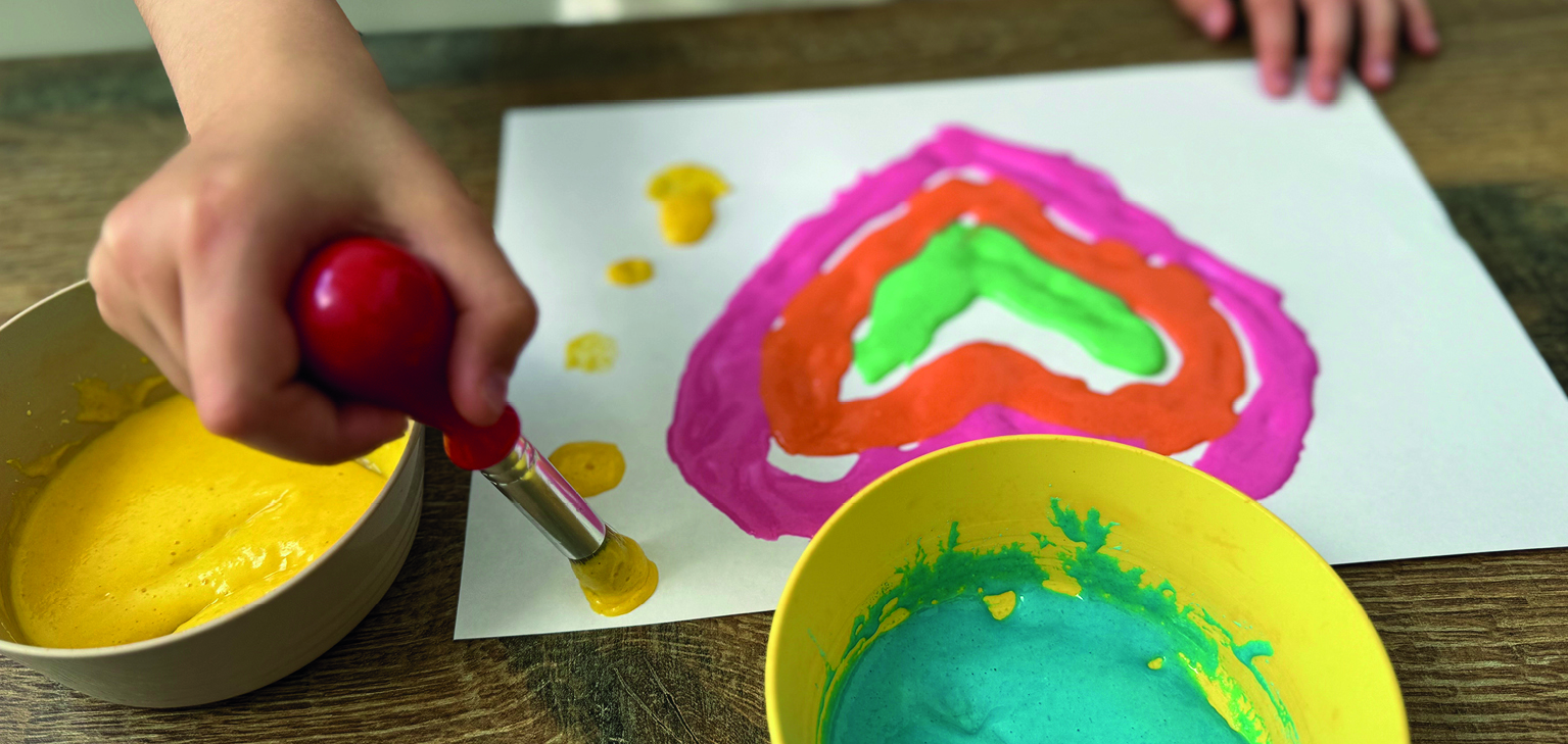 main d'enfant réalisant un dessin à la peinture gonflante