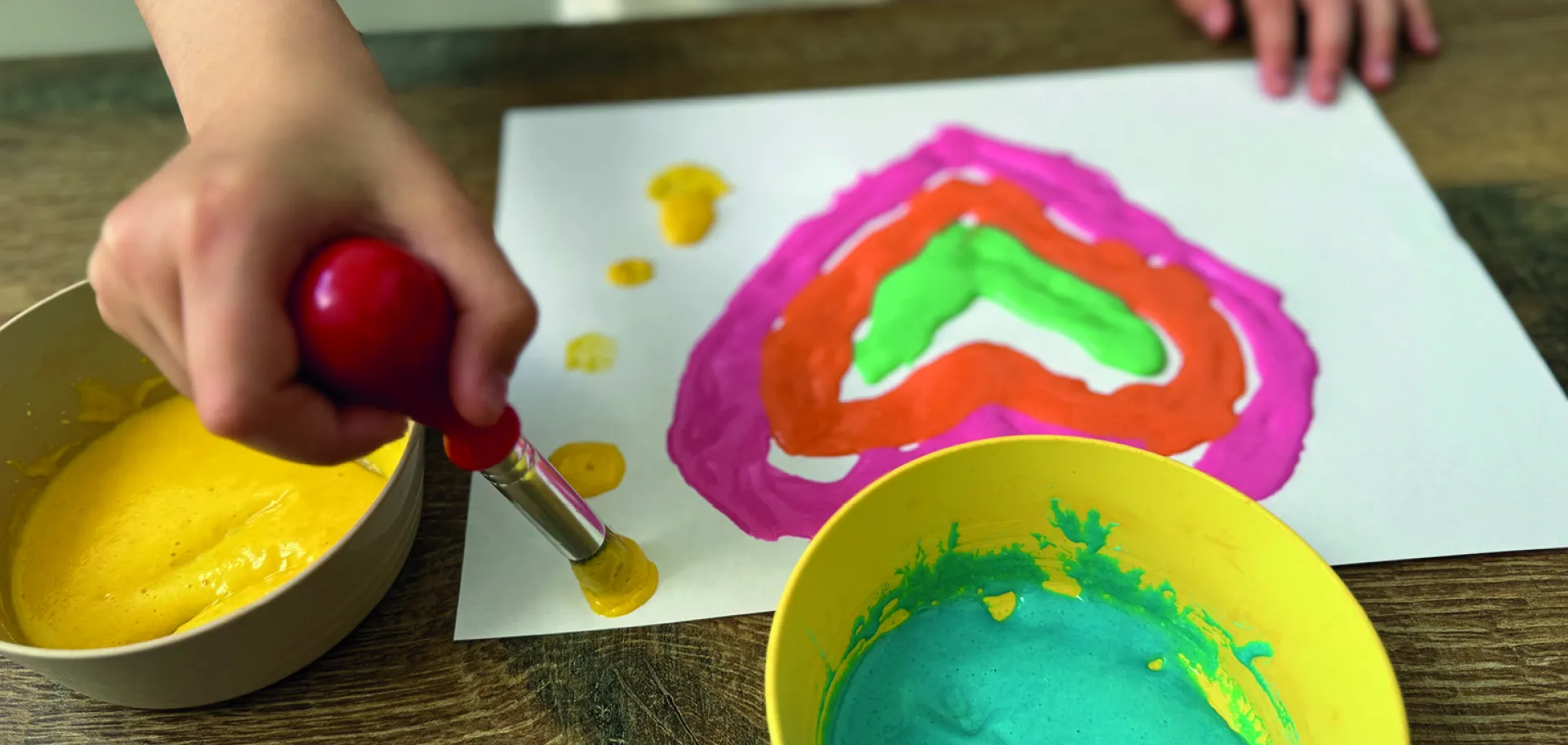 main d'enfant réalisant un dessin à la peinture gonflante