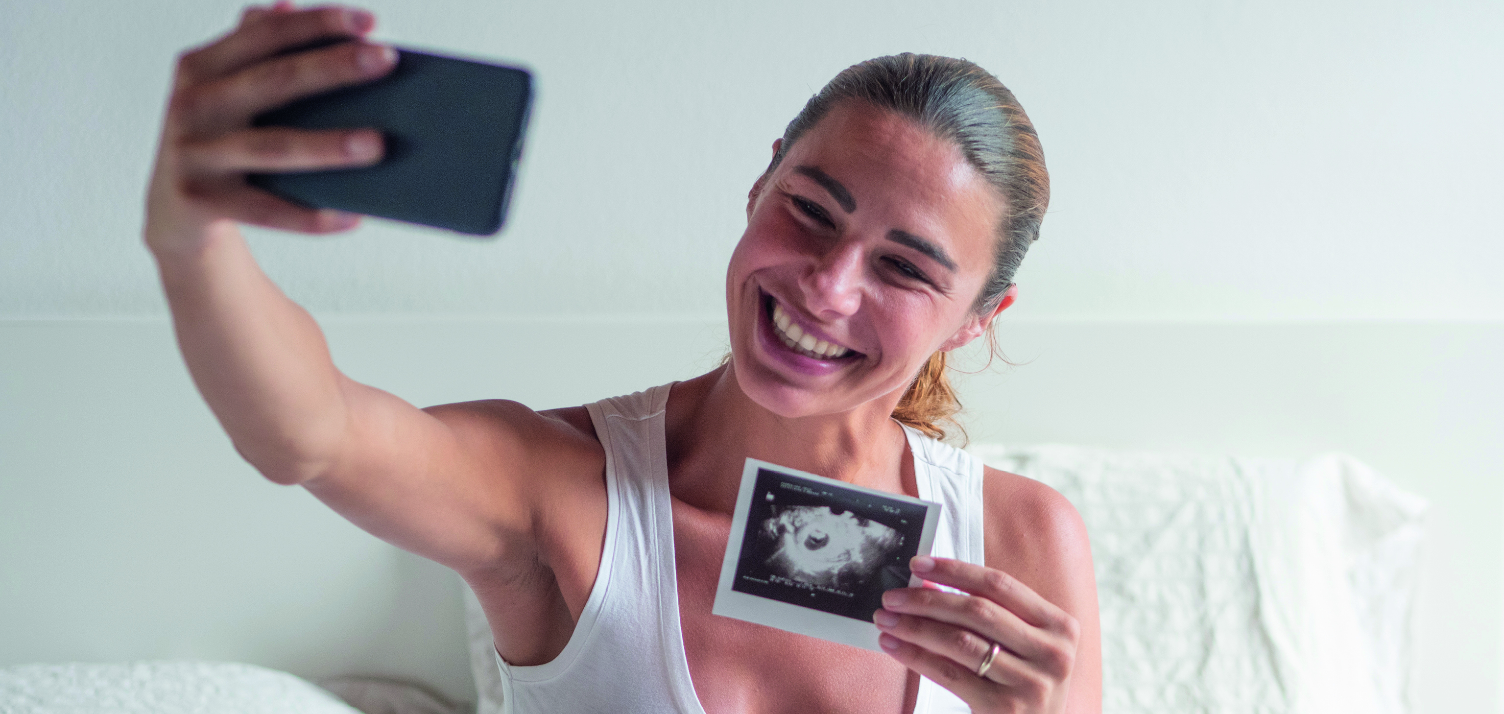 Femme souriante se prenant en photo avec échographie