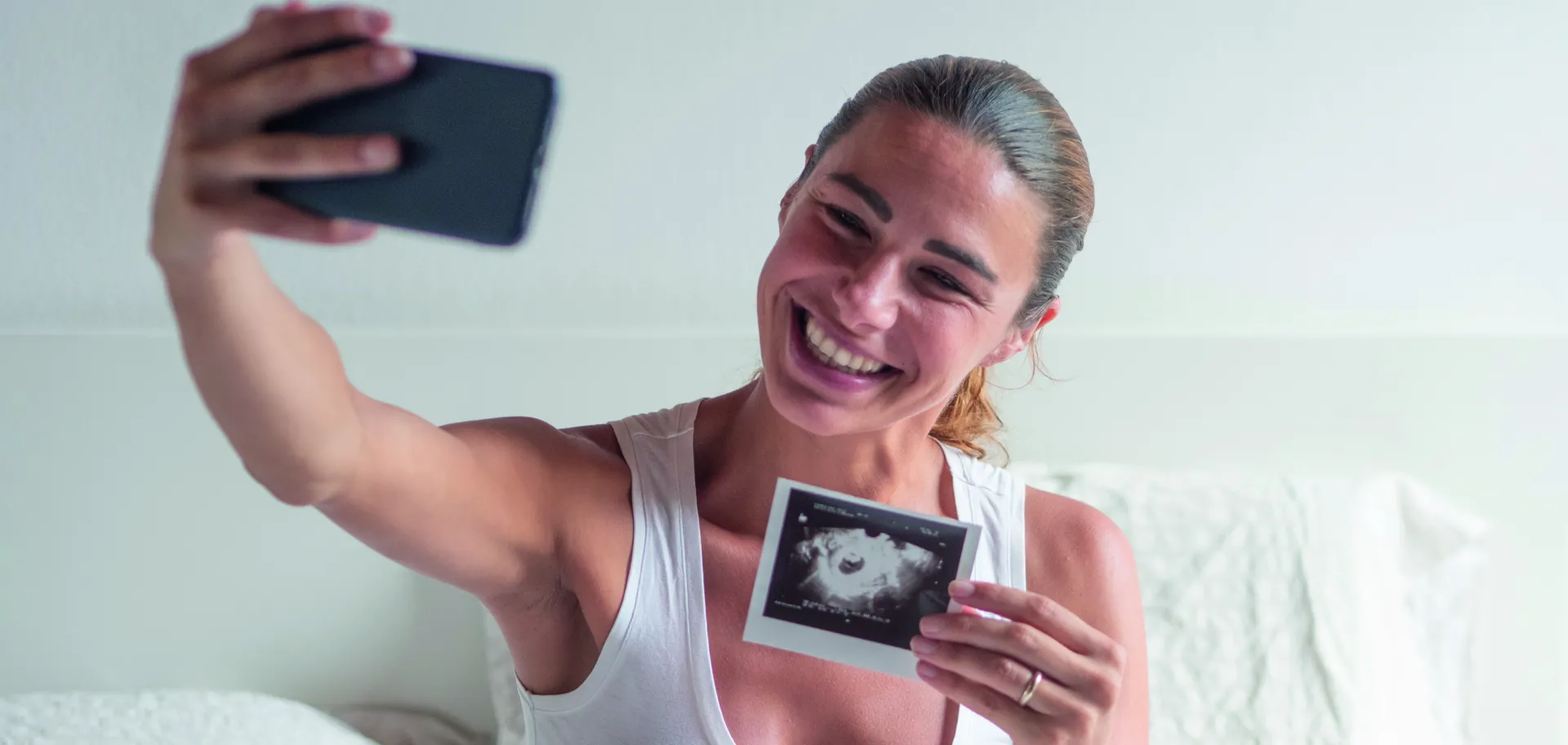 Femme souriante se prenant en photo avec échographie