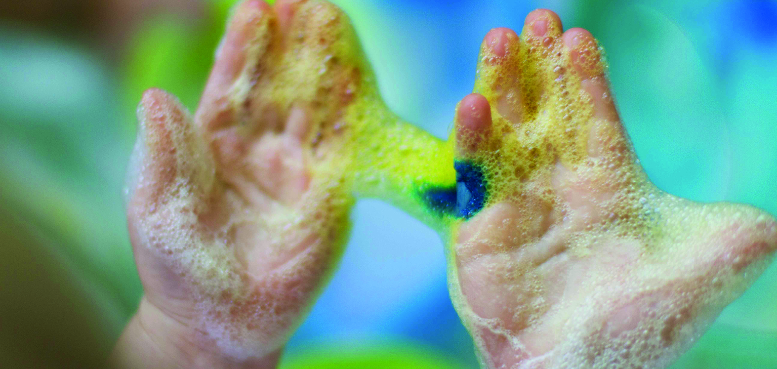 enfant avec mousse colorée sur les mains