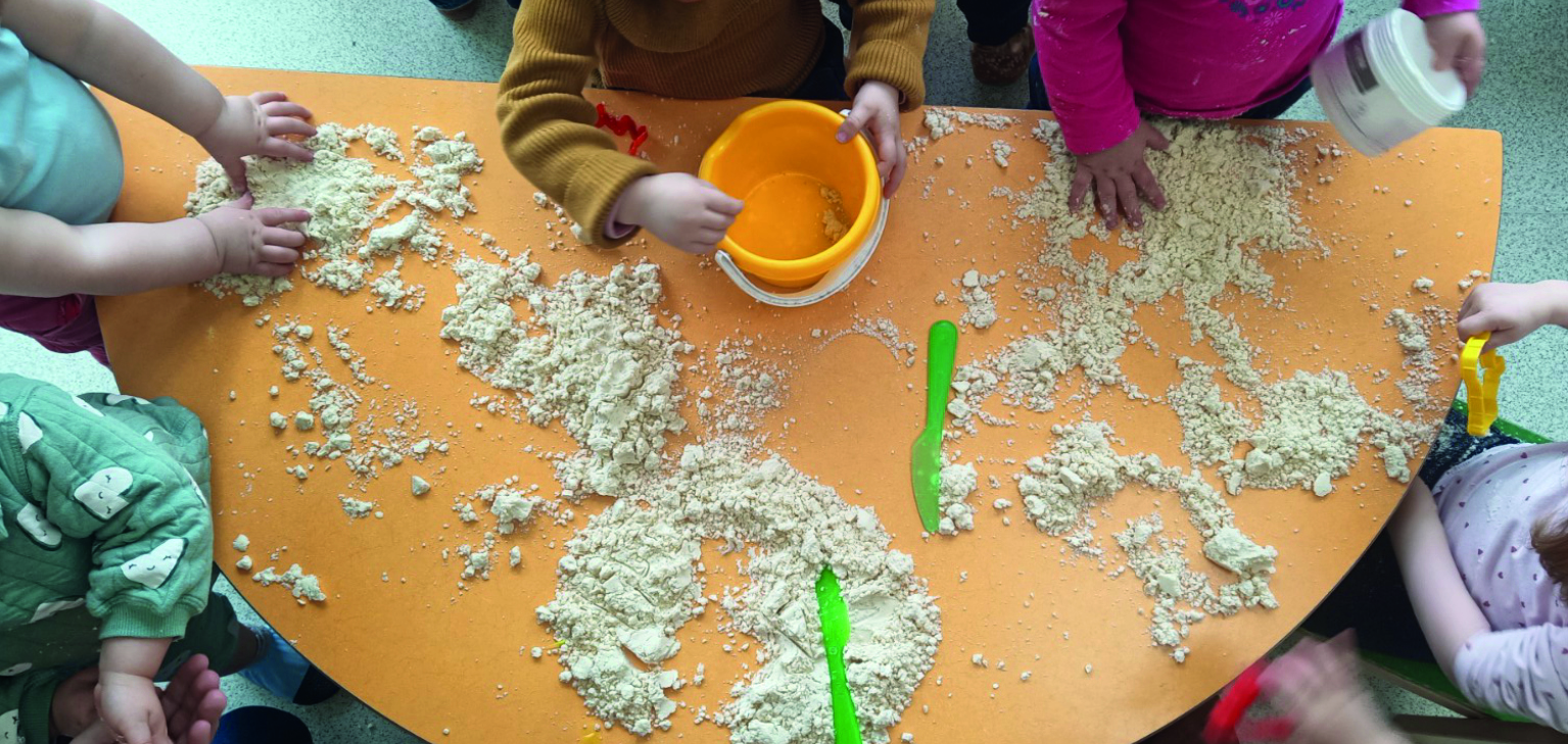 enfants autour d'une table touchant du sable