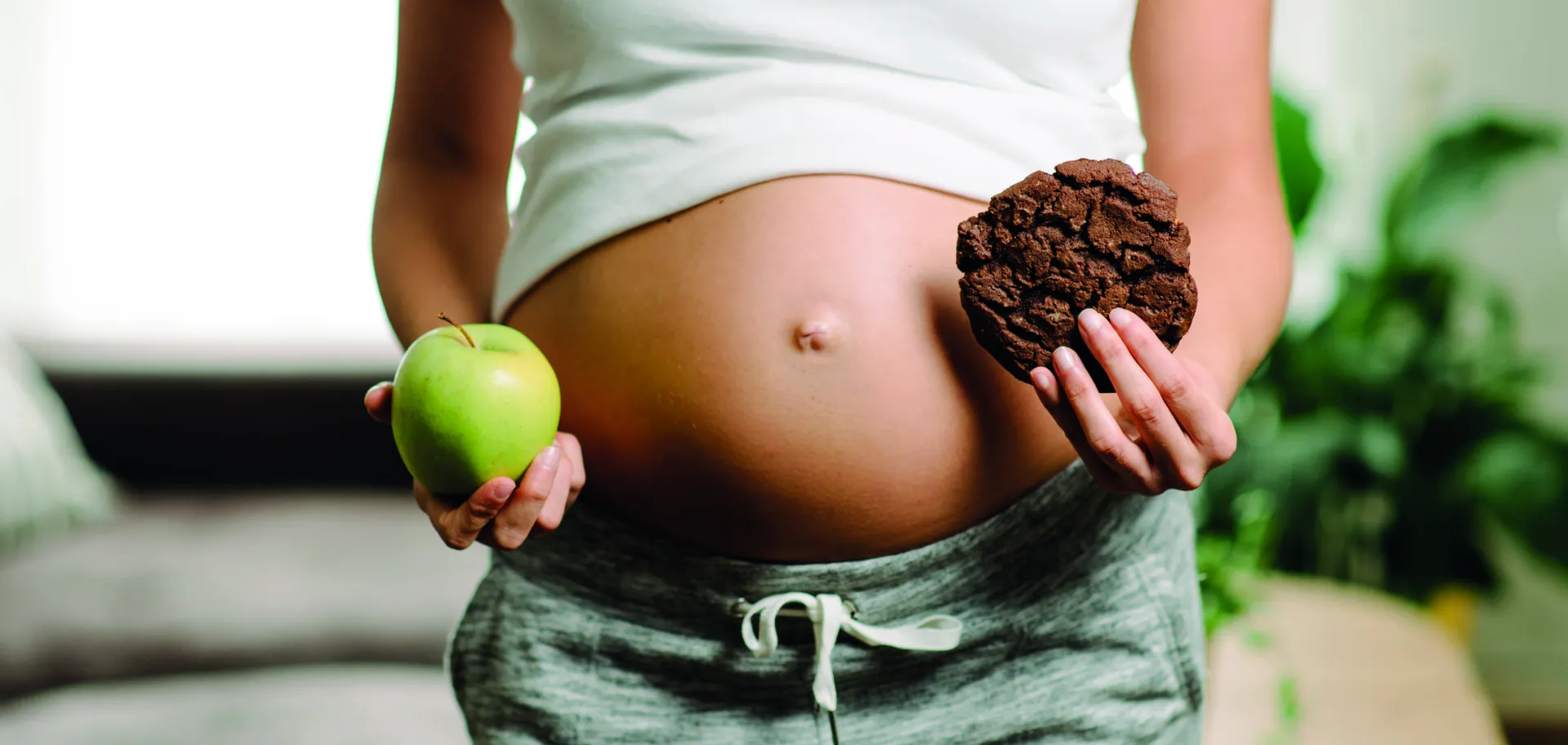 Femme enceinte avec une pomme et un cookie dans chaque main