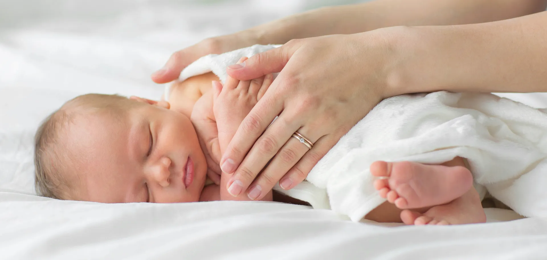 Mains adultes manipulant un bébé endormi