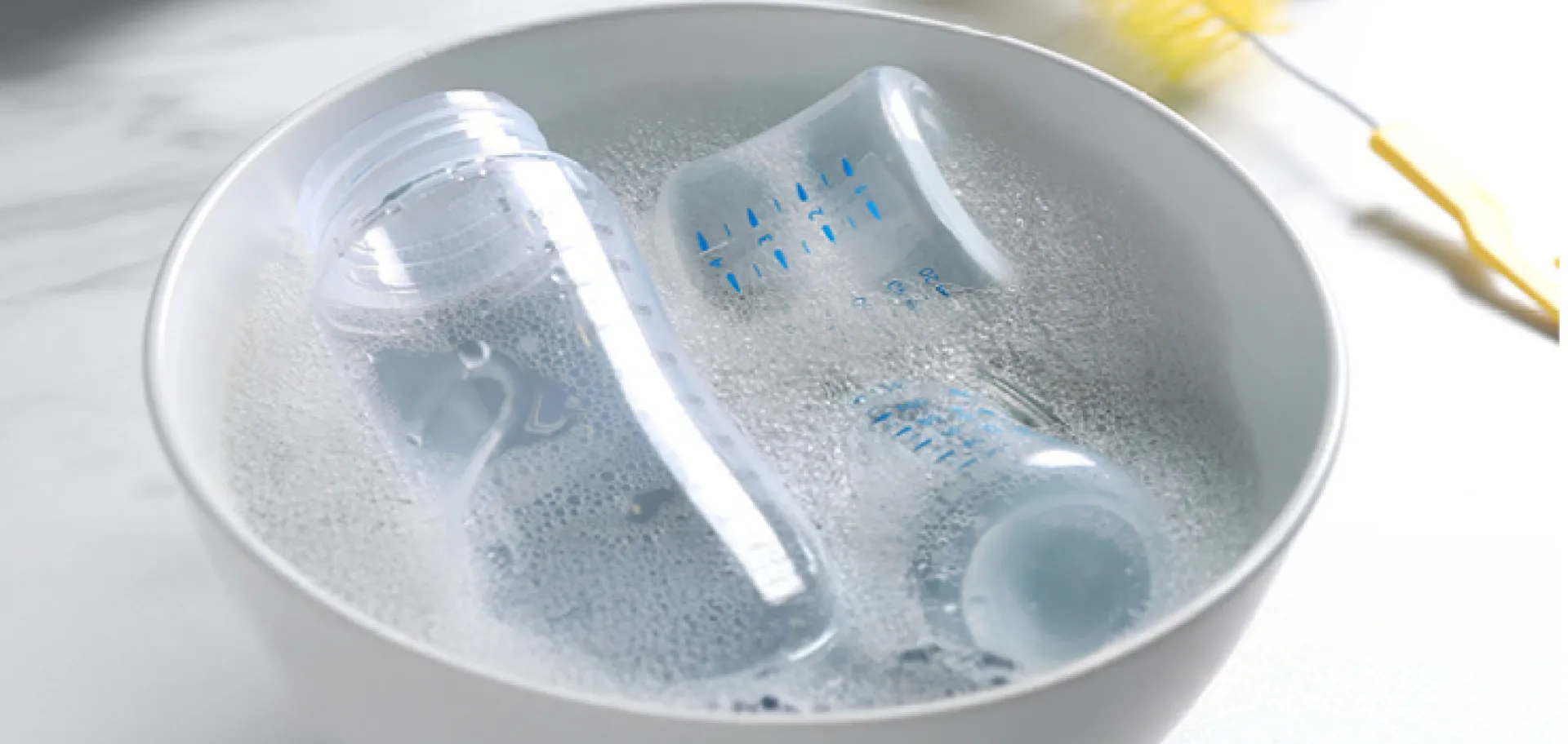 Biberons trempant dans une bassine avec savon