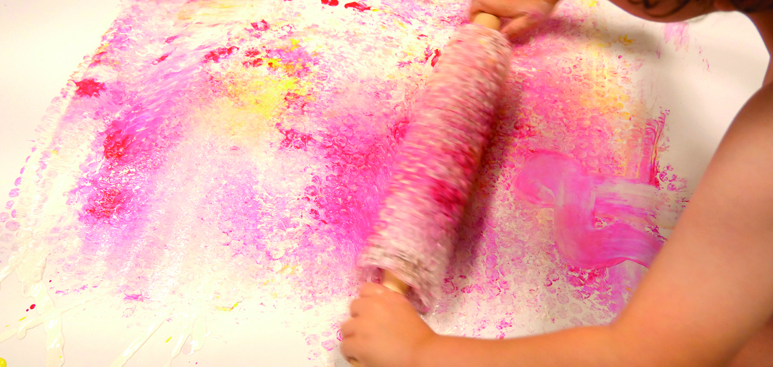 enfant avec un rouleau recouvert de peinture et papier bulle 