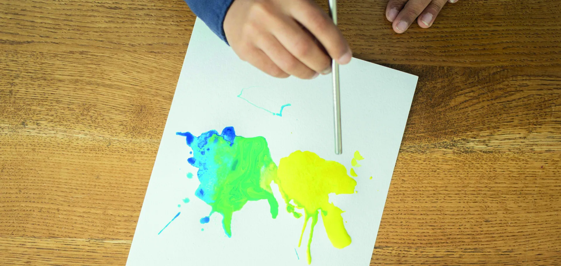 enfant souflant avec une paille sur la peinture