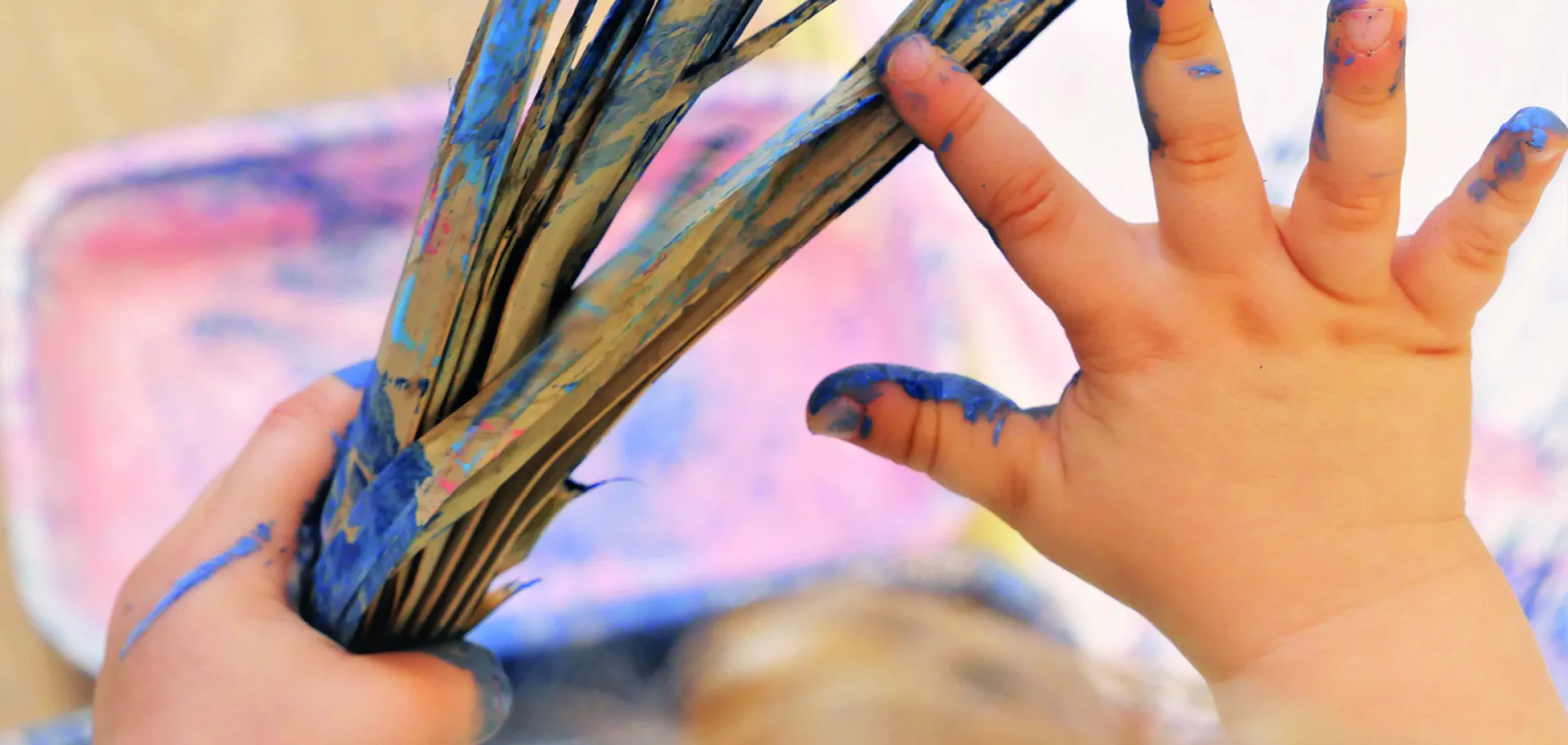 enfant tenant une branche de palmier avec peinture