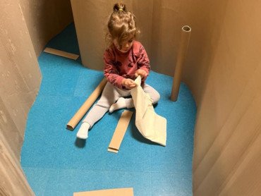 Enfant jouant dans structure carton